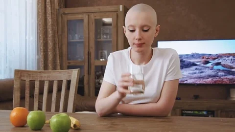 Cancer patient woman sits at the table and drinks glass of water Stock Footage