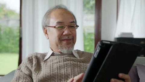 Candid of old asian retired man using tablet computer Stock Footage