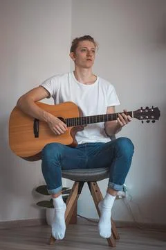 Candid portrait of boy in a white T-shirt and jeans sitting on low stool in c Stock Photos