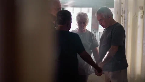 Candid Senior Group Engaged in Prayer, Sun Rays Streaming through Misty Win.. Stock-Footage 244234003