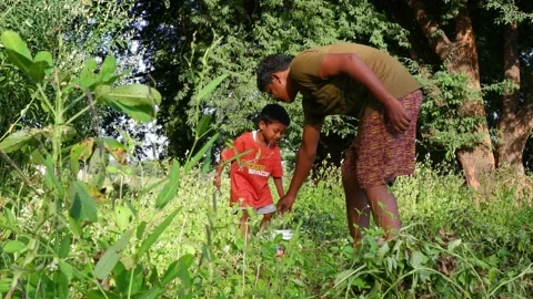 Candid shot of father helping son lifting water cane for gardening Stock Footage 164087009