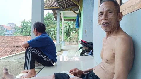 Candid shot of two elderly Indonesian men relaxing and talking. Stock Footage 318599951