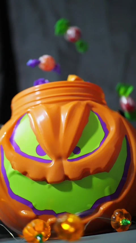 Candies falling into a spooky jack-o'-lantern Halloween candy bucket 스톡 동영상 342521693