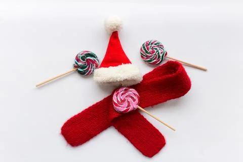 The candies on the white background with red small scarf and small Santa hat 库存照片