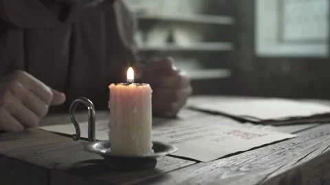 Candle and hands of a scribe placing a page on manuscripts, tracking shot Stock Footage 339231476