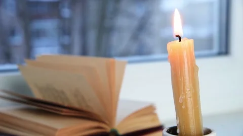 Candle burning and book on windowsill, winter morning Stock Footage 167790629