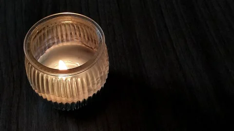 Candle with burning flame goes out on wooden surface Stock Footage