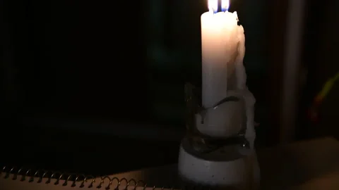 A candle is burning on the table, the camera moves from the candle to a notebook Stock Footage 156756412