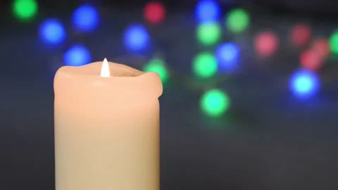 The candle burns against the background of multi-colored lanterns. Stock Footage 165225423