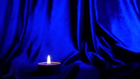 The candle burns against a background of strobing blue and red illumination Stockbeeldmateriaal 233466730
