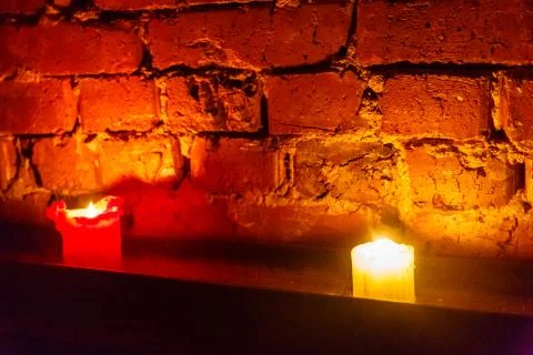 Candle burns on the background of an old brick wall Stock Photos