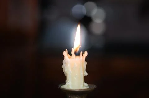 The candle burns on a dark background.  Stock Photos