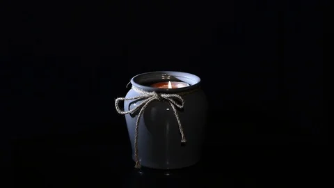 Candle burns in a vase on an isolated black background Stock Footage 124779413