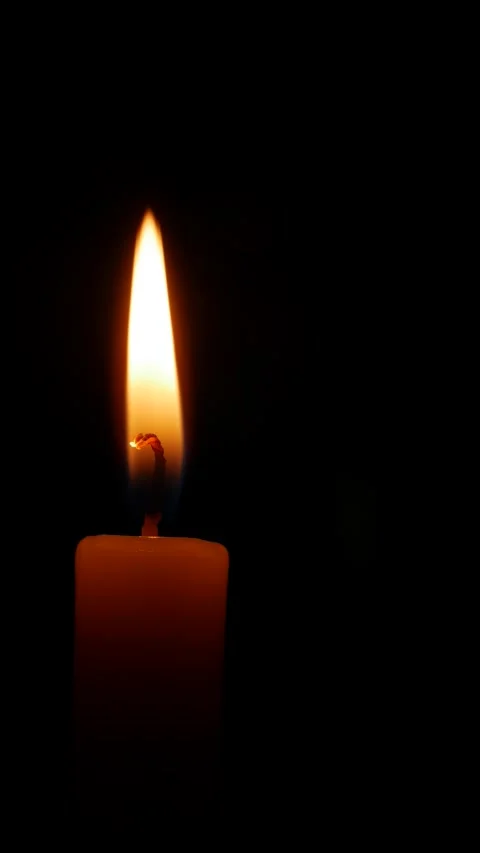A candle burns in a vertical frame its soft trembling flame in total darkness Stock Footage 323439092