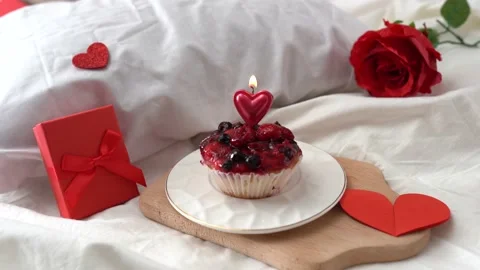 A candle on a cake on the bed with red Valentine decor gifts box and hearts Stock Footage 168396751