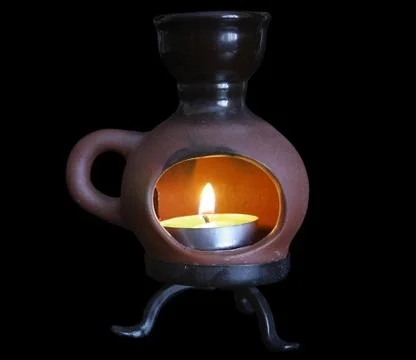 Candle in a ceramic candlestick on black background Stock Photos