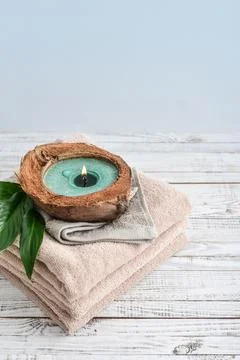 Candle in coconut shell on stack of towels Stock Photos
