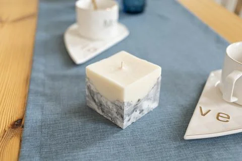 A candle with a concrete base stands on a table Stock Photos