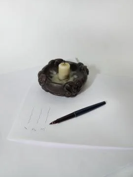 Candle, feather pen on the stack of paper. Inscriptions list Stock Photos