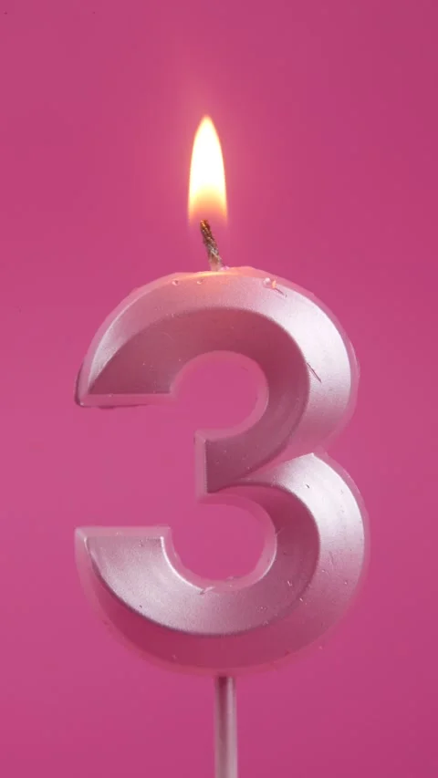 Candle fire at the birthday celebration of a three year old child on a pink Stock Footage 274479324