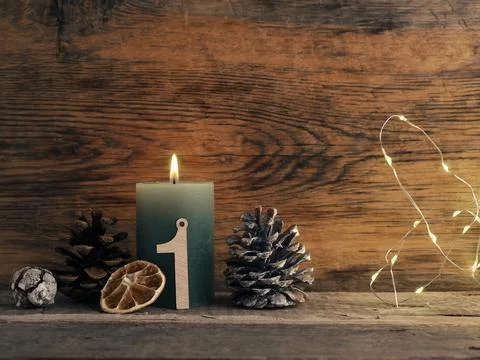 Candle of the first Advent burns, pine cones and Christmas decoration on wood Stock Photos