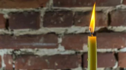 Candle flame close-up on a light red wall background. Melted Wax Candle light Stock Photos