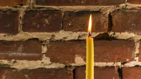 Candle flame close-up on a light red wall background. Melted Wax Candle light Foto stock