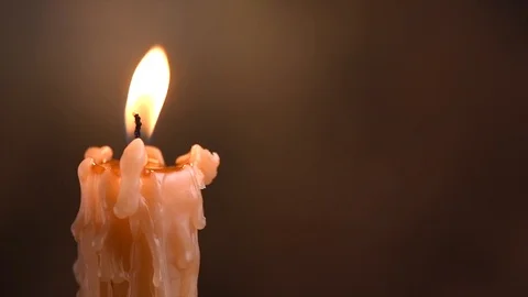 Burning candle with melting wax close-up on a black background