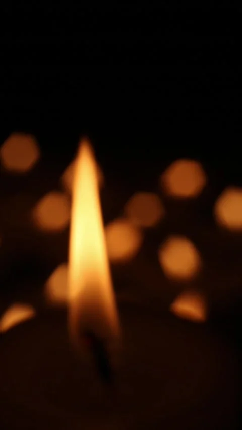 Candle flame with distant bokeh lights in dark ambience Video stock 323863988