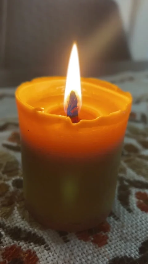 A candle flame flickers on a decorative surface, creating a cozy ambiance and Stock-Footage 306076454