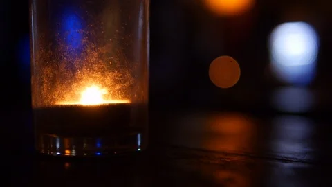 Candle flame in the glass, placed on a wooden table, has a light as a background Stock Footage