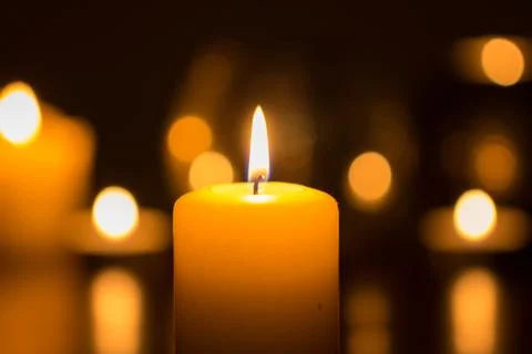 Candle flame glowing in darkness Stock Photos