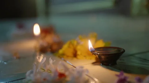 Candle flames flicker among vibrant flower offerings on temple altar at night Stock Footage 269034869
