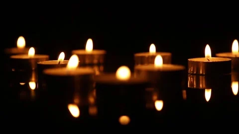 Candle flames with smooth focus shift in dark reflective scene Vídeo Stock 339620685