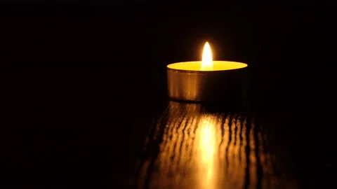 The candle flickers in the dark A white round candle burns on a dark background Stock Footage 172310683