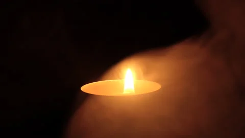 The candle flickers in the dark A white round candle burns on a dark background Stock Footage 172312022