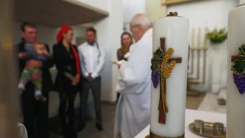 Candle focus: Baptism process in a catholic church with priest and newborn's Video stock 219901659