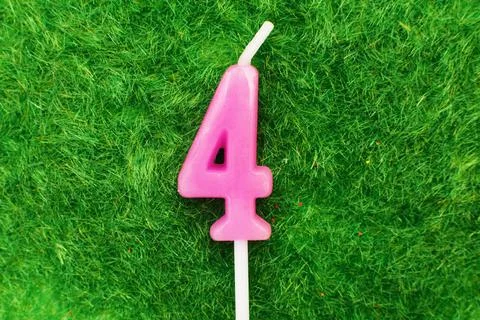 Candle in the form of number 4 on the green grass background, a place for a g Stock Photos