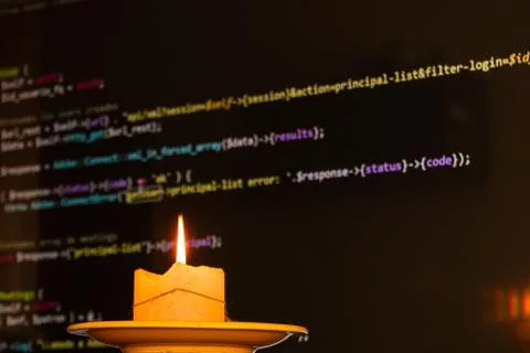 Candle in front of the screen displaying computer codes 스톡 사진