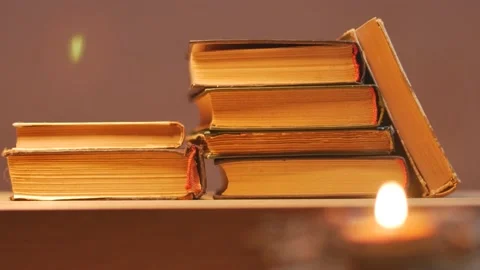 Candle in front of a stack of vintage books Stockbeeldmateriaal 173610562