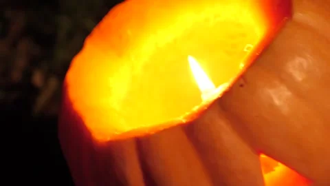 A candle glows in a pumpkin at night close-up. Halloween celebrations 스톡 동영상 253311286