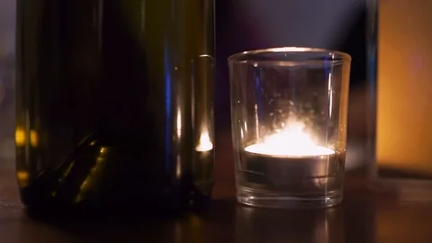 Candle light in restaurant table by green glass wine bottle romantic dark Stock Footage 92762289