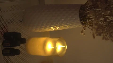 A candle lights a dim room, revealing shadows of dried flowers Stock Footage 304870202