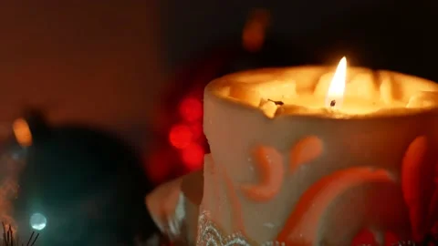 Candle is lit against the background of blinking gerlands and cristmas balls Stock Footage 143381699