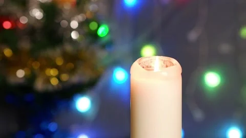The candle is lit on a blurred background. Decorated Christmas tree with lamps. Stock Footage 169646318