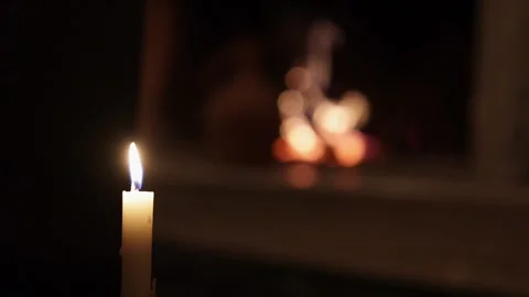Candle is lit in the dark with a blurry background of a window and a candle Stock Footage 230558273