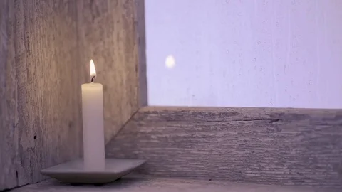 Candle lit on the window sill of an old window, it rains outside Stock Footage 74723627