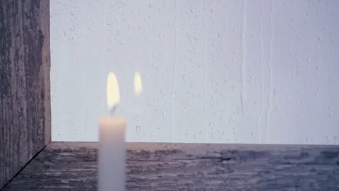 Candle lit on the window sill of an old window, it rains outside Stock Footage 74723628