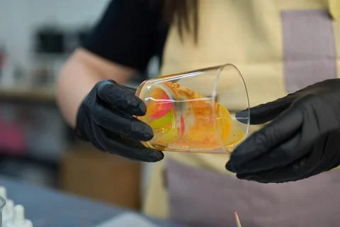 Candle maker adding colorful wax to glass jar in workshop Stock Photos