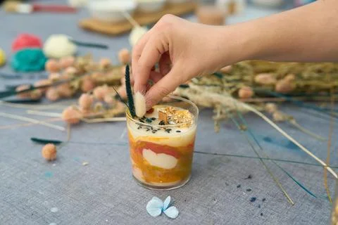 Candle maker adding decorative dried flowers to a handmade candle in her Stock Photos